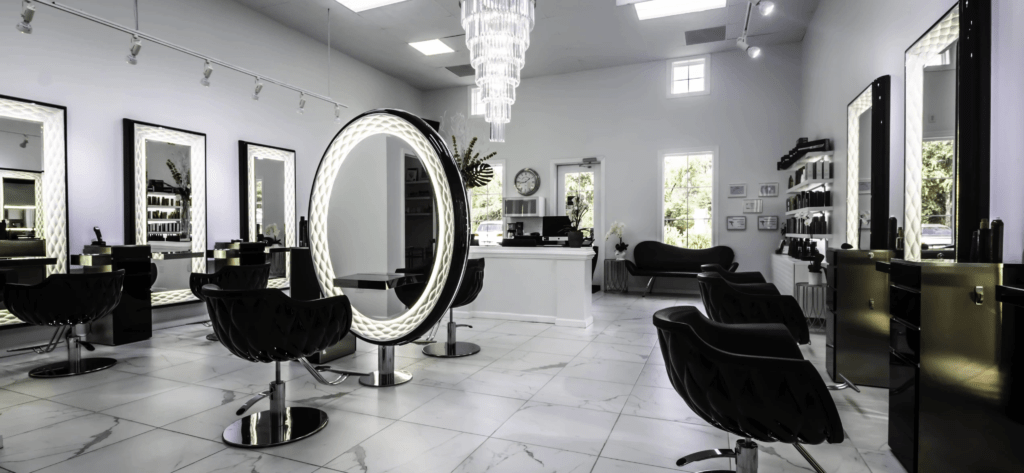Upscale salon suite interior with crystal chandelier and lighted mirror at Aura Beauty Suites in Colorado Springs.